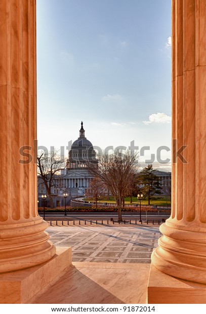 Stock photo of the US Capitol Dome framed by the solid columns of the Supreme Court in Washington DC