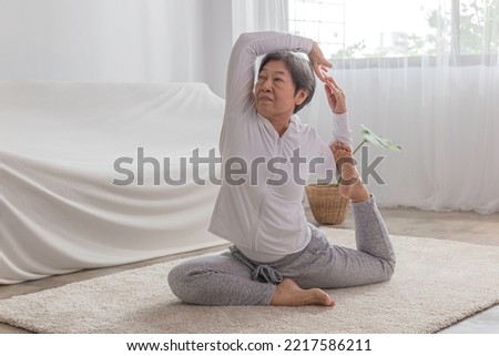 late age woman attractive white and gray sportswear practicing and exercise in yoga style in room ,learn pigeon pose yoga lesson. 