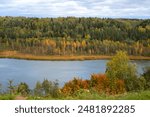 Late autumn in a wild forest area. Low rain clouds over trees on the horizon. Aerial drone shot. Winter moody wood view. Distant mysterious nature landscape. Woodland Valley with a Lake in the far.