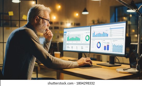 Late Evening Business Office: Creative Middle Aged Analyst Works on Desktop Computer, Doing Final Report, Working with Charts, Graphs. Modern Business Office - Powered by Shutterstock