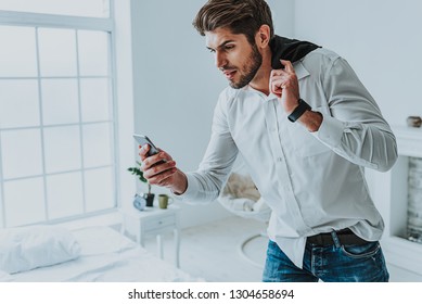Late For Meeting. Waist Up Portrait Of Worried Man In Panic Looking To Mobile Phone While Hurry Up On Work