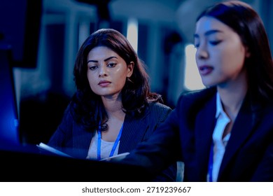 Late night code warriors Two female developers intensely debugging code together, eyes locked on the screen, determined to solve a complex issue before the product launch.