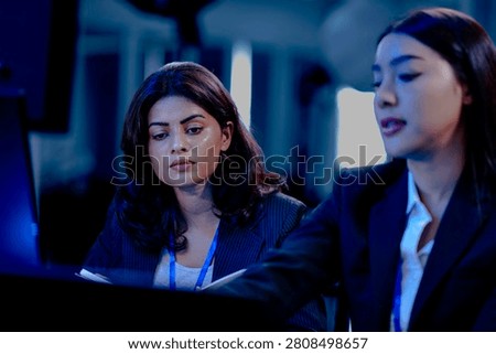 Late night code warriors Two female developers intensely debugging code together, eyes locked on the screen, determined to solve a complex issue before the product launch.