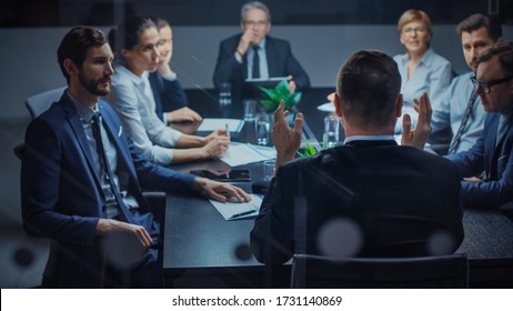 Late at Night In the Corporate Office Meeting Room: At Conference Table Executive Director Talks to a Board of Directors, Investors and Business Associates. Over the Shoulder Shot.