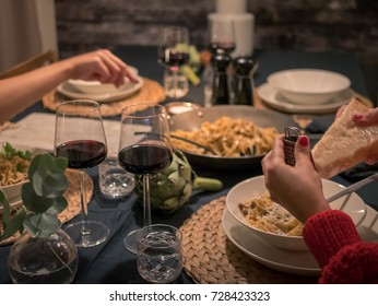 Late Night Dinner At Home. Friends Eating Pasta And Drinks Wine At Table.