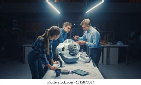 Late at Night in Robotics Engineering Facility Three Technical Engineers Talk and Work on a Wheeled Robot Prototype. In the Background High Tech Research Center with Screens Showing Industrial Design - Shutterstock ID 1515878387