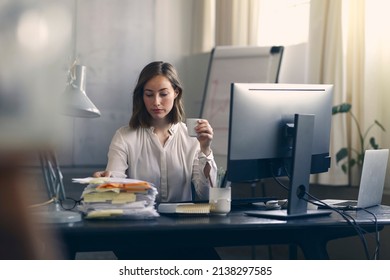 Late night working business woman looking at a the large pile of work while drinking coffee to keep her awake.	Busy with all that work before deadline.  - Shutterstock ID 2138297585