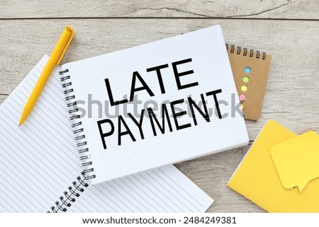 LATE PAYMENT light background text on an open notepad near a yellow pen