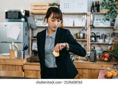 Late For The Upcoming Meeting, The Busy Asian Business Woman Checking The Time On Watch And Have The Breakfast Rushly Late.