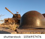 A late WW2 helmet in front of an M47 Patton tank at sunset.