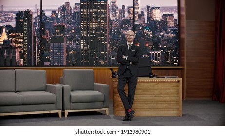 Late-night Talk Show Host Is Leaning Against His Table In Studio, Looking Into Camera. TV Broadcast Style Show