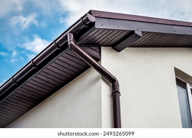 Lateral coated metal panel, rain gutter and rain water pipe at a roof in sunny day