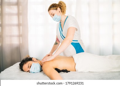 Lateral Plan Of A Professional Woman Of Caucasian Ethnicity Giving A Physiotherapeutic Back Massage Wearing A Face Mask Due To The Covid 19 Coronavirus Pandemic