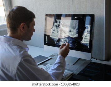 Lateral View Of A Male Radiologist Examining Neck X-rays (cervical Vertebrae) On Computer