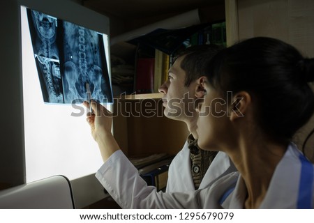 Lateral view: picture of two doctors exploring spinal x-ray: lumbar and cervical region - first 2 cervical vertebrae (axis and atlas), coxofemural joint