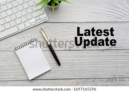 LATEST UPDATE text with notepad, keyboard, decorative vase and fountain pen on wooden background. Business and copy space concept