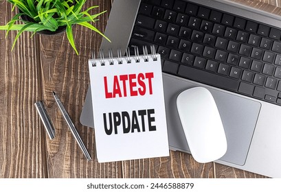 LATEST UPDATE text on a notebook with laptop, mouse and pen . 
