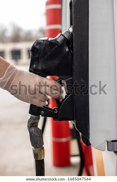 Latex Gloved hand pumping\
gas