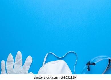 Latex Gloves, Protective Mask And Glasses On Blue Background. Safety Equipment. Copy Space. Top View