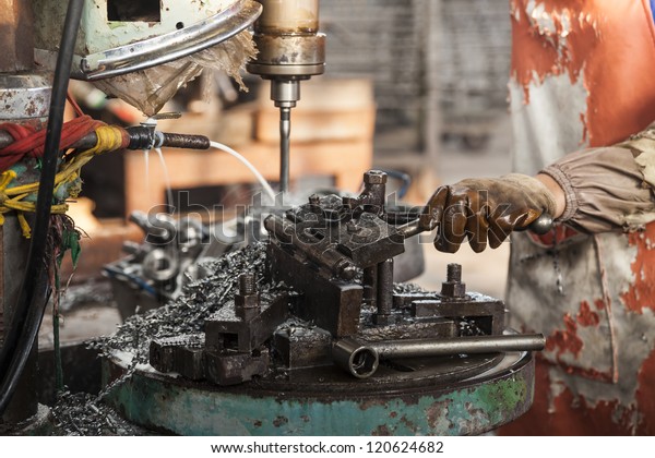 lathe machine in a car spare parts work shop,\
worker working with the\
machine