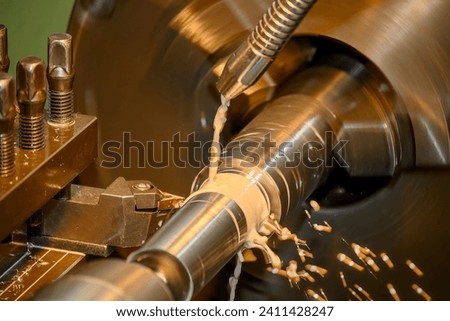 The lathe machine finish cut  metal shaft parts with liquid coolant method. The metalworking process by turning machine.