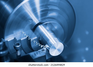 Lathe Tool Bit And Spiral Swarf At Working On Metal Product In Blue Toned Background. Closeup Of Steel Knife With Carbide Insert In Holder Of Turning Machine. Chip Machining With Motion Blur Or Bokeh.