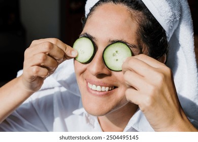 Latin adult woman applying facial mask on face with cucumber slices for exfoliation at home in Mexico Latin America, hispanic people - Powered by Shutterstock