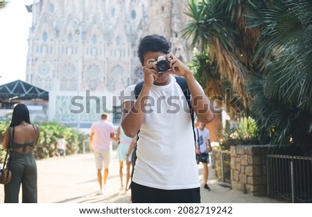 Latin amateur using vintage camera for catch photo focus during touristic trip to Barcelona, professional photographer taking images of Catalonia streets in Spain standing near Sagrada Familia
