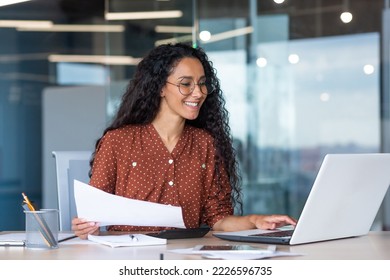 latin american businesswoman working inside office with documents and laptop, worker paperwork calculates financial indicators smiling and happy with success and results of achievement and work