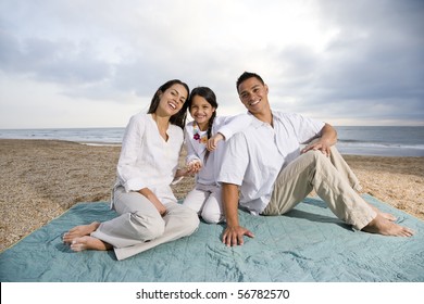 Latin American Family With 9 Year Old Girl Sitting On Blanket At Beach