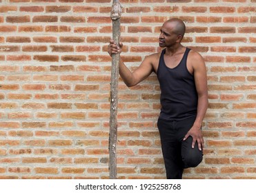 Latin American fitness man standing leaning on brick wall