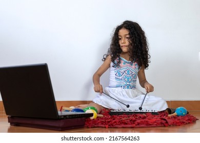 Latin American Girl Receiving Her Virtual Music Class Playing A Xylophone