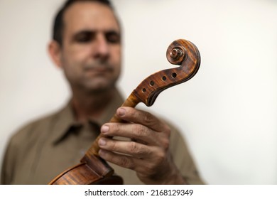 Latin American luthier holds an unfinished violin in his hands, selective focus on the violin. Concept stringed instruments