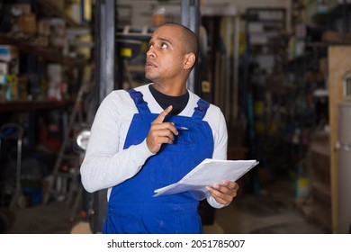 Latin American Male Warehouse Worker Making Notes While Performing Inventory Of Building Materials