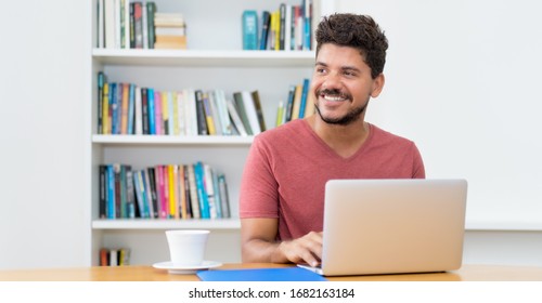 Latin American Man With Beard Working At Computer At Home