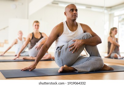 Latin american man practicing Matsyendrasana known as Lord of Fishes Pose during group yoga training