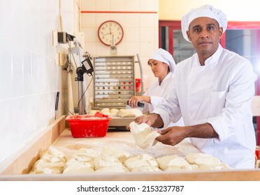 Latin American Man Working With His Wife In Family Bakery, Forming Bread Loaves From Raw Dough