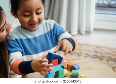 Latin American Mother And Son Child Having Fun Playing Games With Wood Toy Blocks At Home - Family Time Together