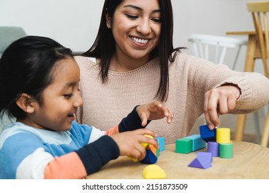 Latin American Mother And Son Child Having Fun Playing Games With Wood Toy Bricks At Home - Family Time Together