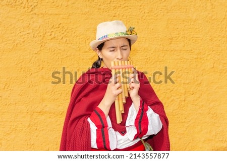 Latin American peasant woman with hat and red shawl playing the panpipe