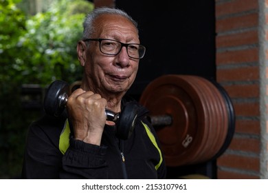 Latin American Senior Male Does Rehabilitation And Therapy Exercises Holding A Dumbbell In The Gym. Healthy Lifestyle Concept.