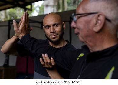 Latin American Senior Male And His Trainer Performing Rehabilitation And Therapy Exercises In The Gym. Healthy Lifestyle Concept.