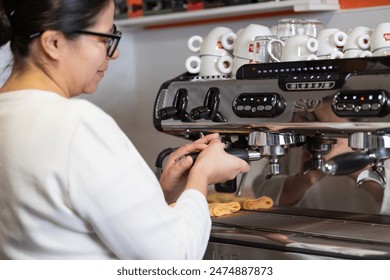 Latin American woman professional barista preparing coffee in her Italian professional espresso machine in her cafeteria - Powered by Shutterstock