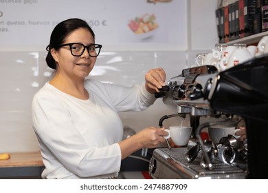 Latin American woman professional barista preparing coffee in her Italian professional espresso machine in her cafeteria - Powered by Shutterstock