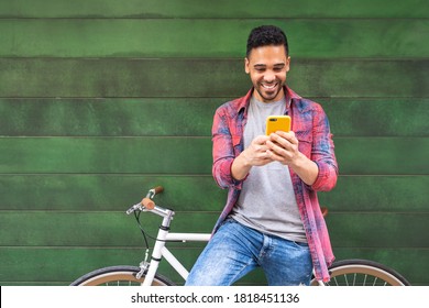 Latin American Young Man Using Phone Outdoors. Latino Man Texting On Cellphone In The Street. Lifestyle Concept.