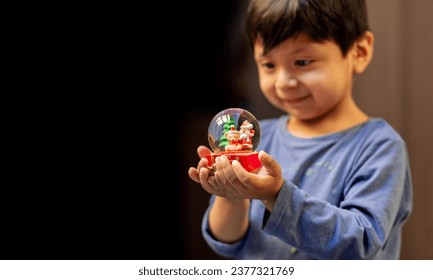 Latin boy holding a Christmas snow globe in his hands. copy spac - Powered by Shutterstock