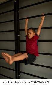 Latin Child Holding Body Weight With Arms On Crossbar, Lifting Legs Up. Full Body Workout, Train Every Muscle, Getting Stronger Every Day. Gym, Health, Physical Exercise, Sport Concept