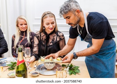 Latin Cook Serving Food To Clients At Table During Private Dinner At Home. Chef Serving Sushi To Stylish Group Of People.