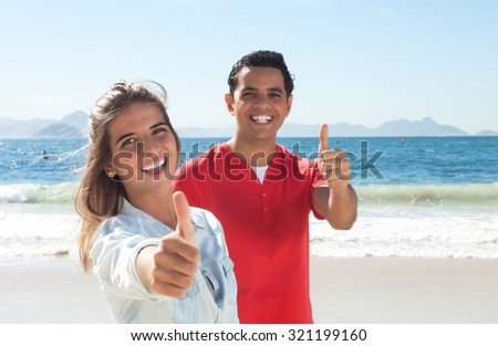 Latin couple at beach showing thumb up