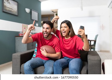 Latin Couple Cheering While Watching American Football Match At Home